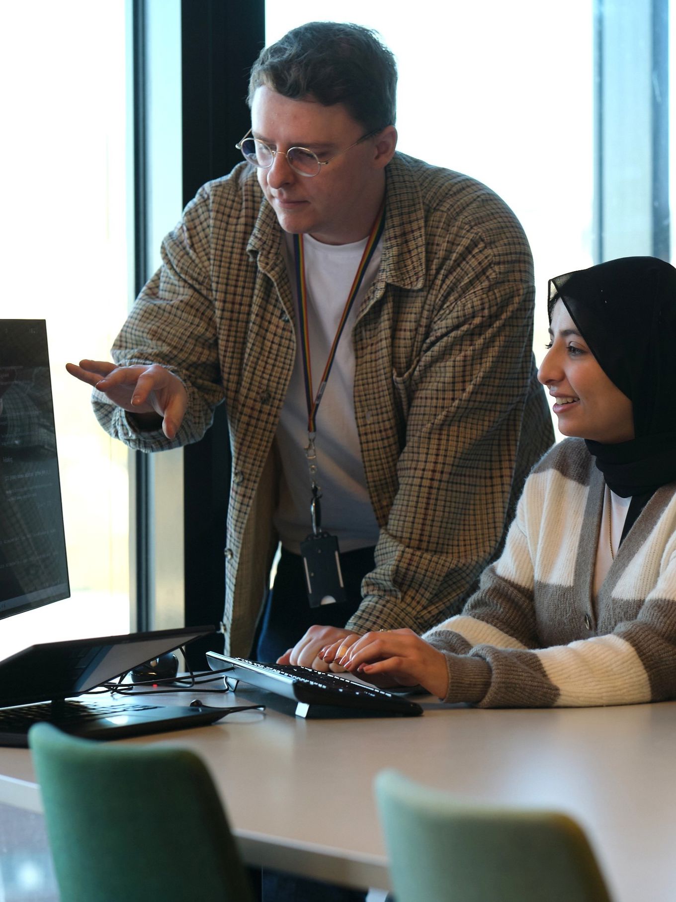 En lærer og en elev som ser på en dataskjerm