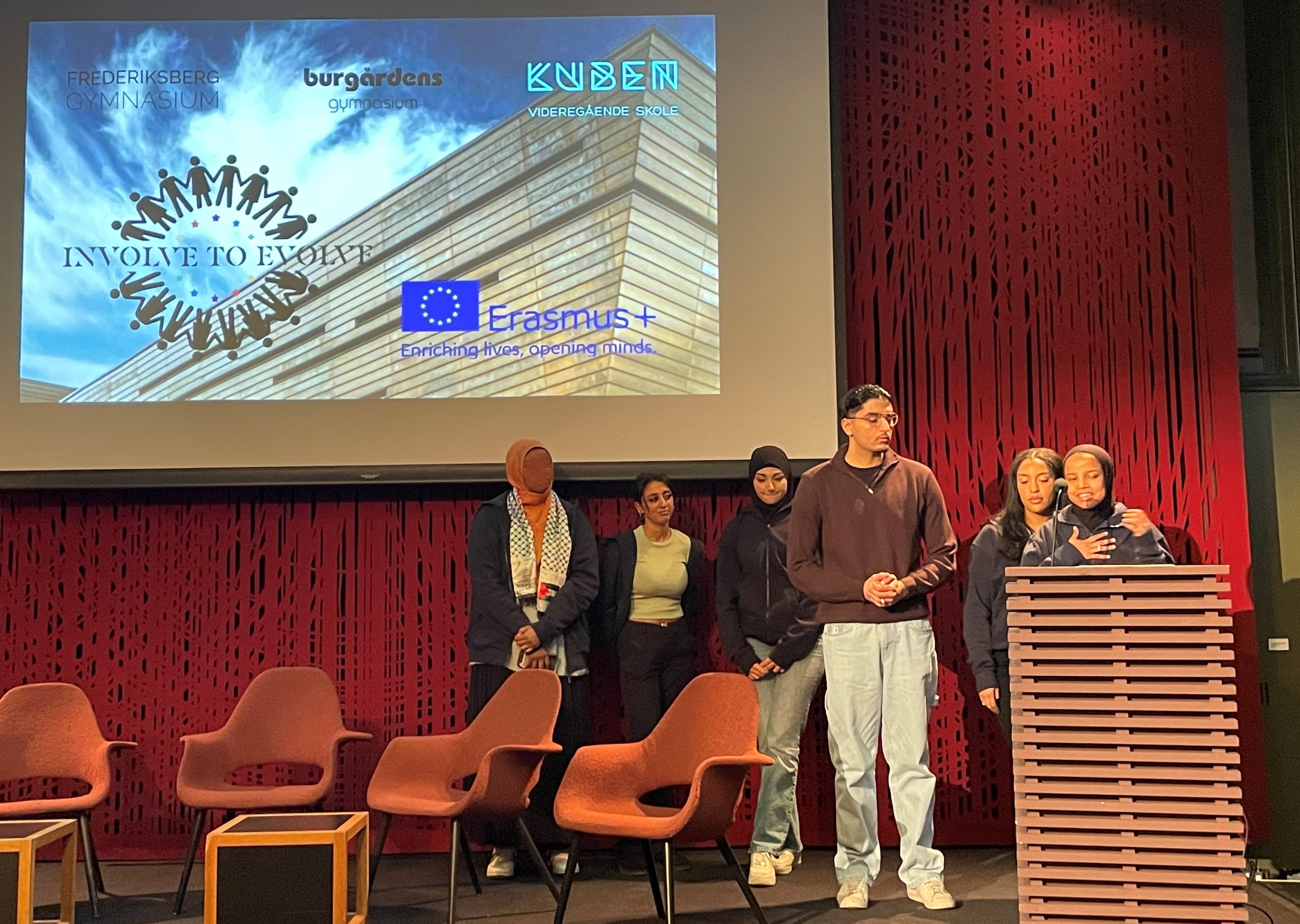 Involverte elever presenterer sine erfaringer en gruppe mennesker som står på en scene
