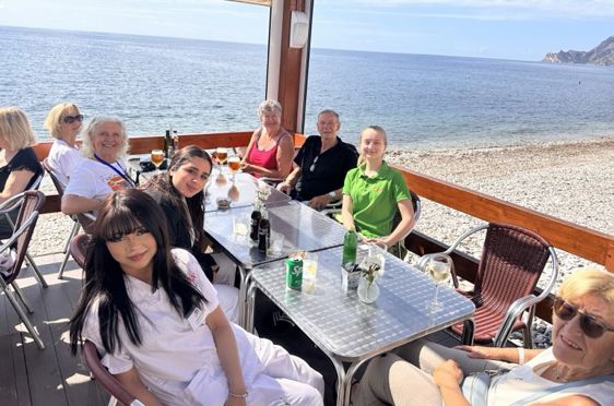 en gruppe mennesker som sitter ved et bord på stranda