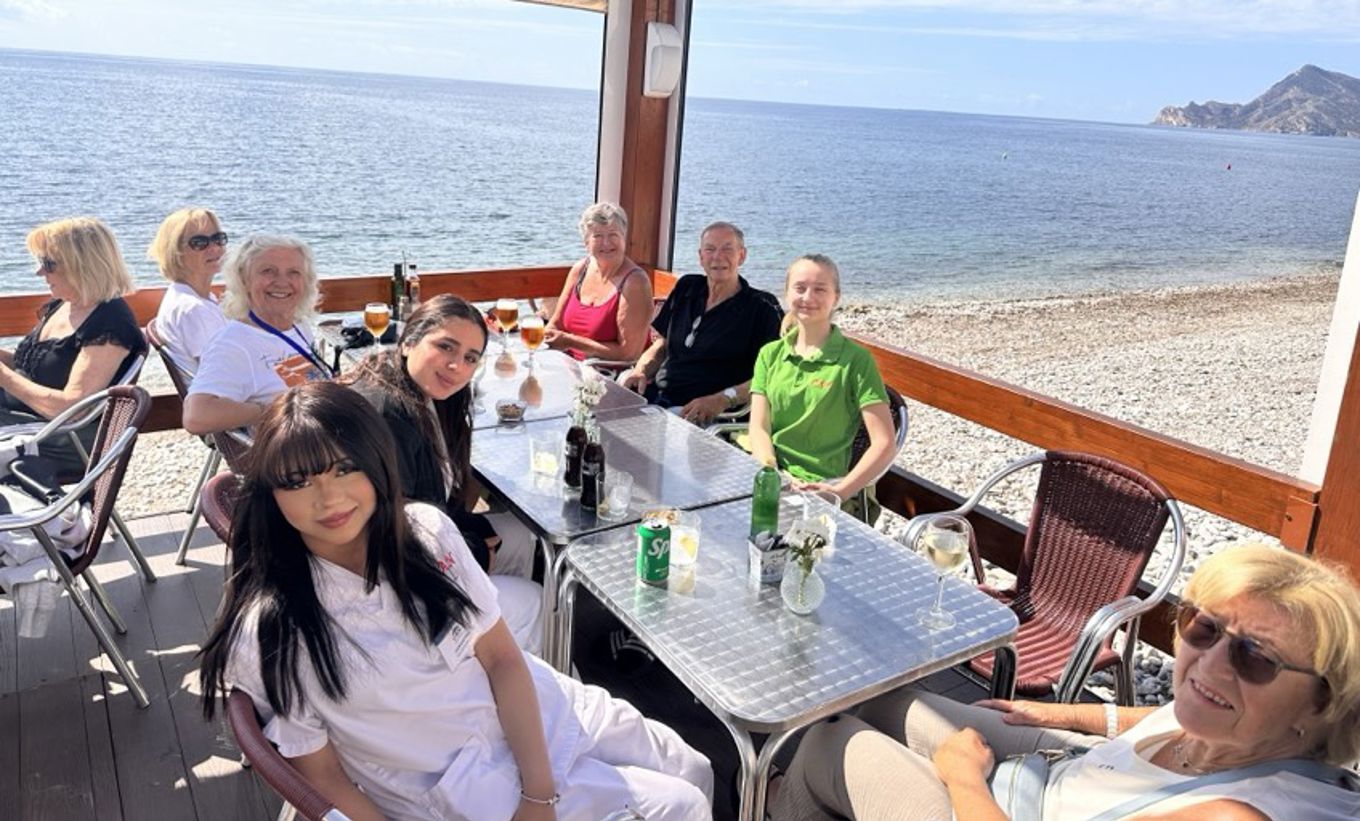 en gruppe mennesker som sitter ved et bord på stranda