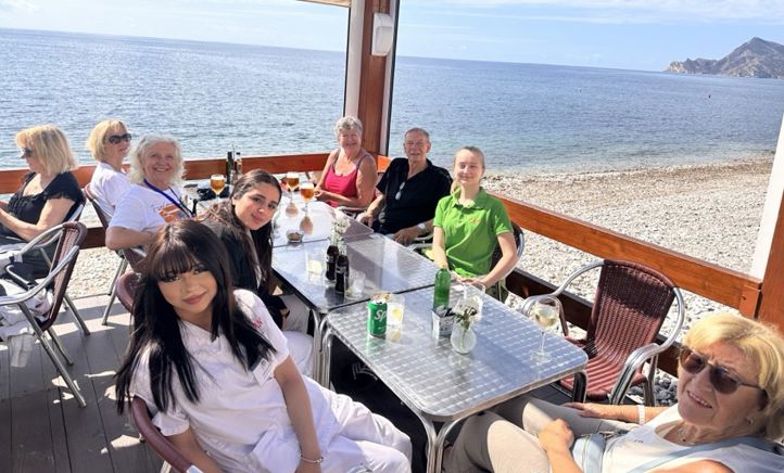 en gruppe mennesker som sitter ved et bord på stranda