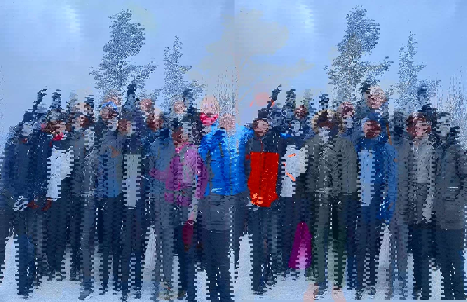 en gruppe mennesker som poserer for et bilde i snøen