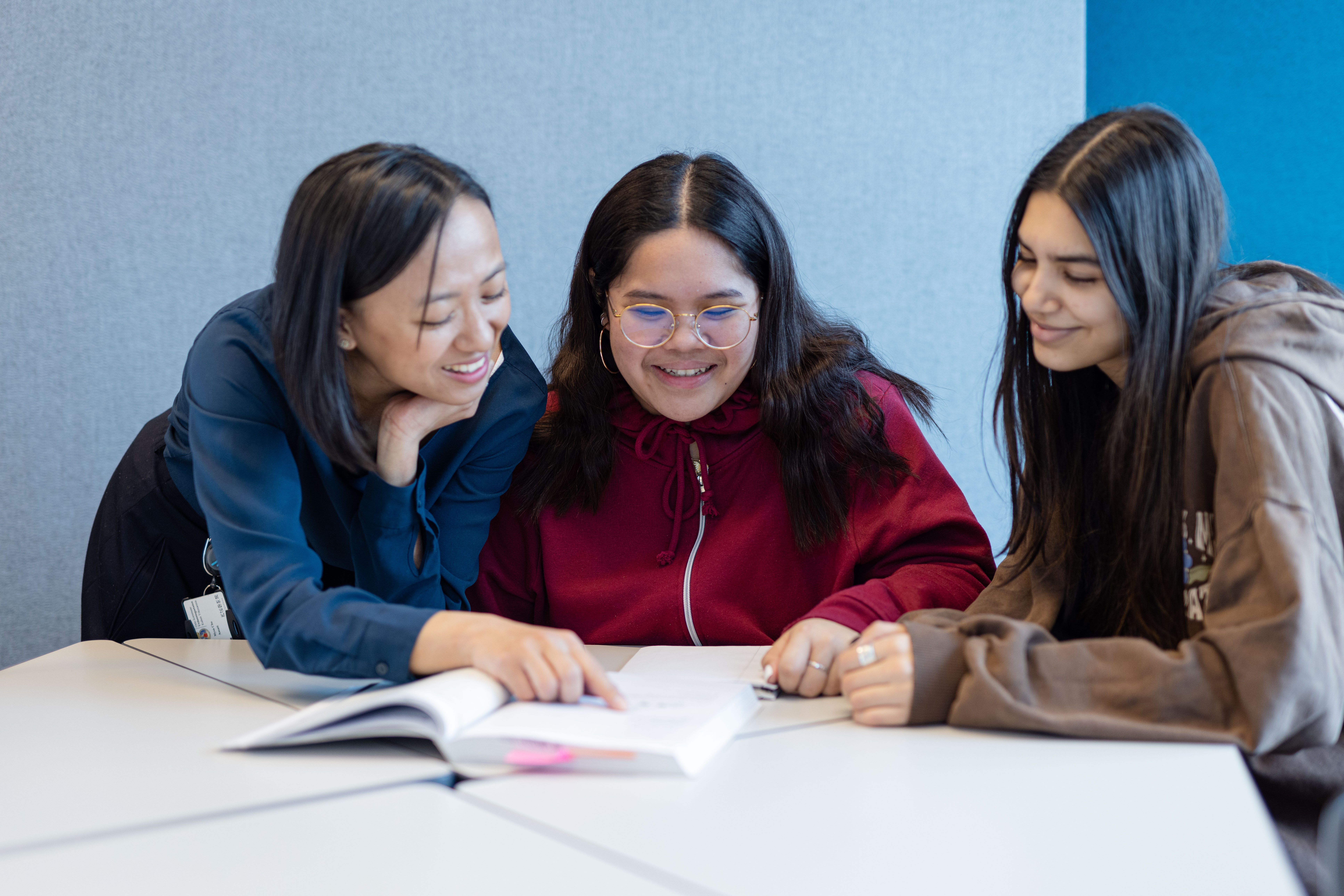 en gruppe personr som sitter ved et bord og ser på papirer