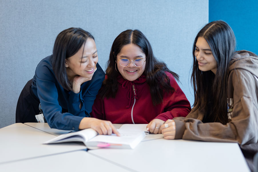 en gruppe personr som sitter ved et bord og ser på papirer