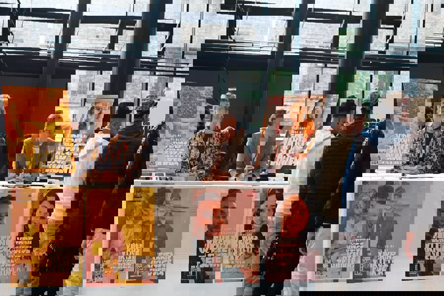 en gruppe mennesker som står rundt et bord med plakater på