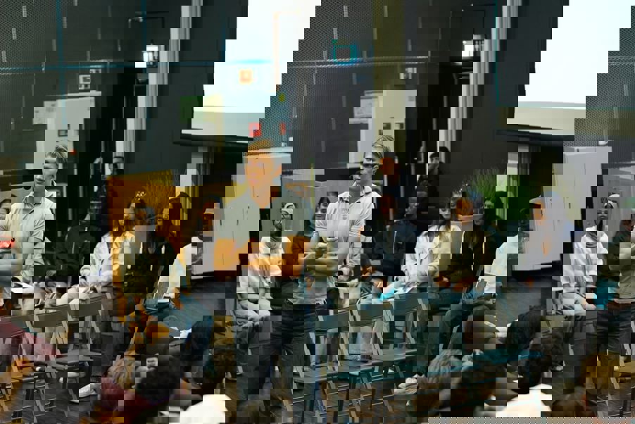 en person som står foran en gruppe mennesker som sitter i stoler