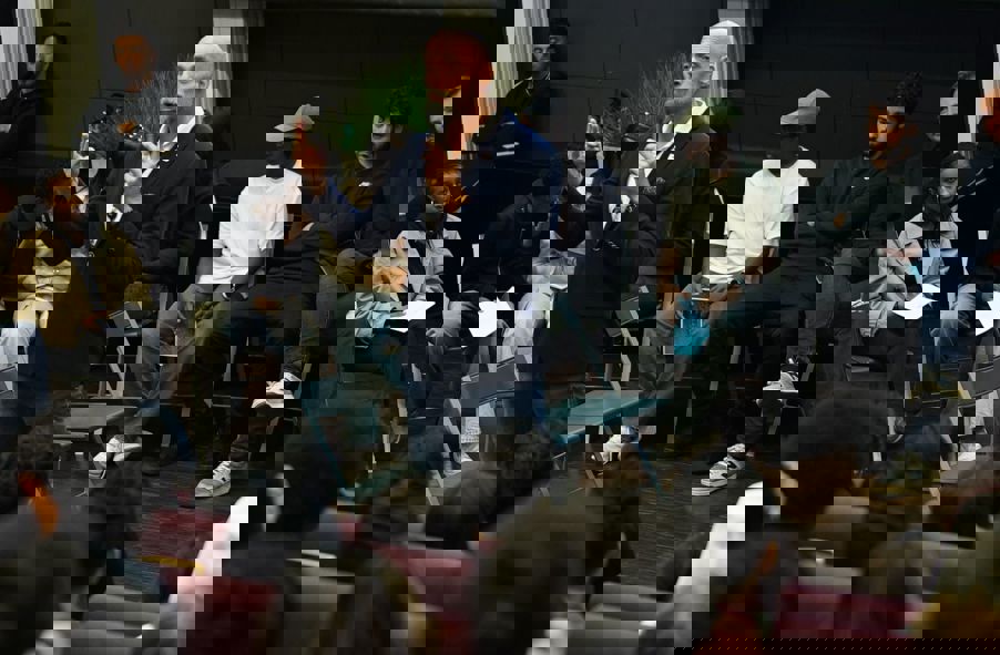 en person som snakker inn i en mikrofon foran en gruppe mennesker