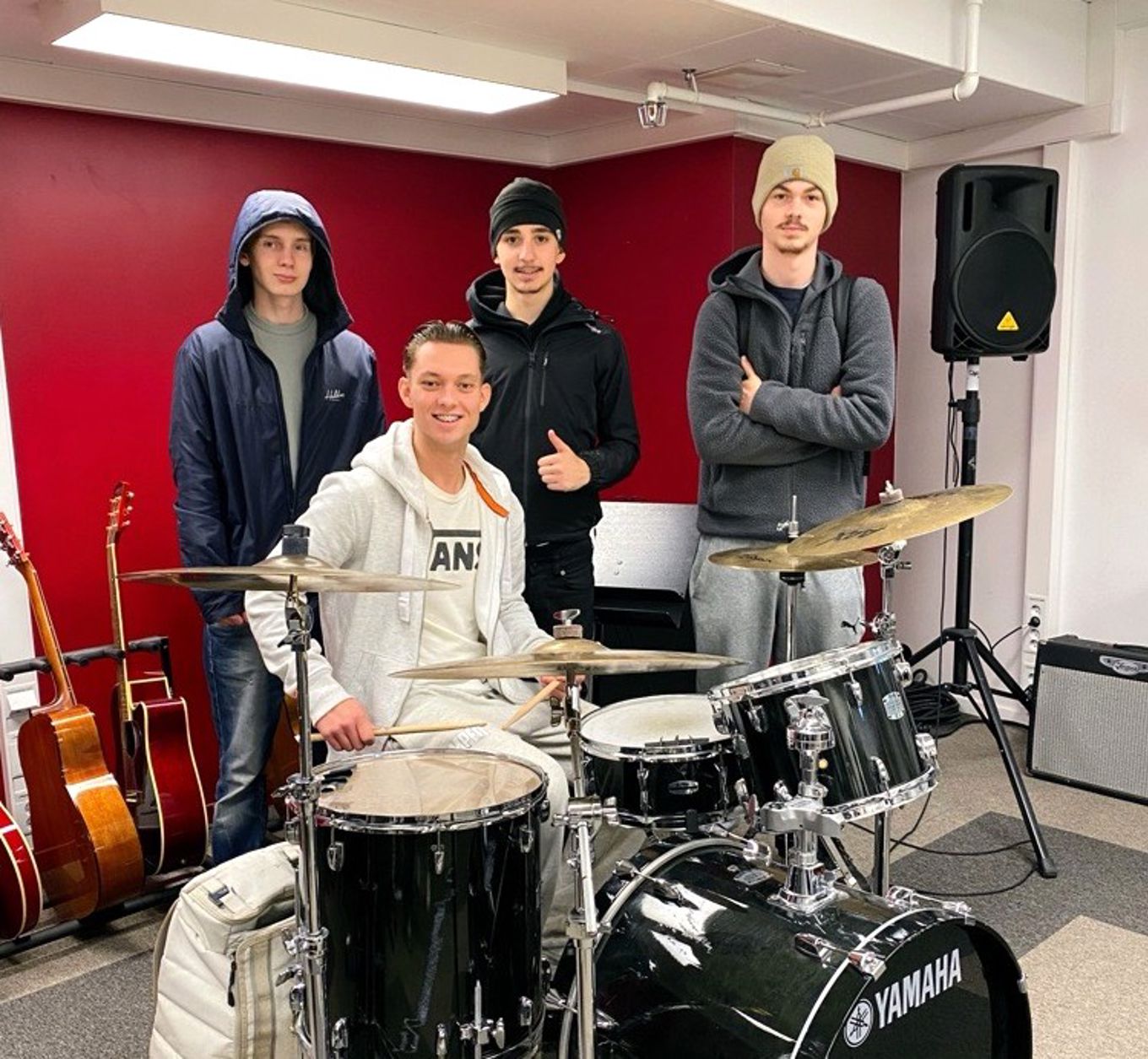 Foto: Bak fra venstre Linus, David-Enis og Lucas fra Vg2, med Ole Marius fra Vg1 på trommer. en gruppe mennesker som står ved siden av et trommesett