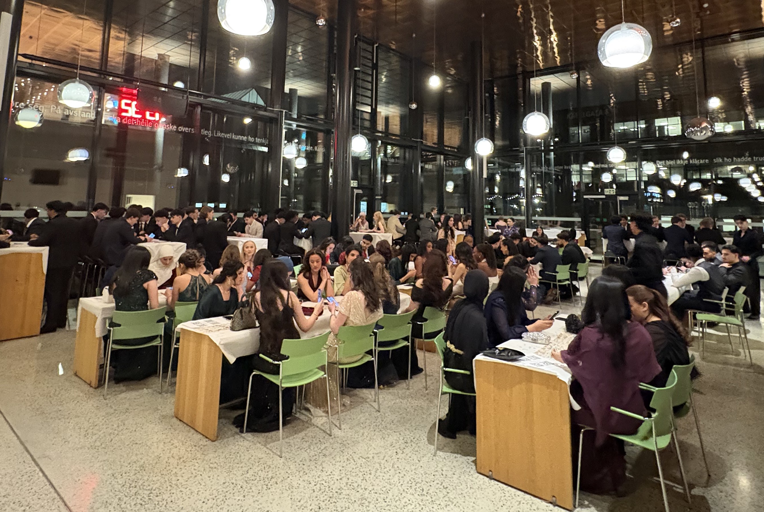 en stor gruppe mennesker som satt ved bord i et stort rom